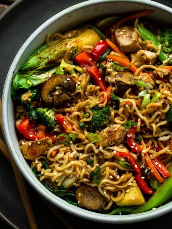a photo of a large bowl fill of yakisoba noodle with stir fried vegetables including red peppers, mushrooms, chicken chunks, baby bok choy