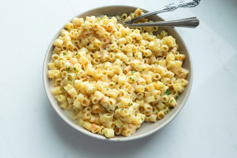 Overhead view of creamy butter pasta tossed with Parmesan in a large white ceramic bowl.
