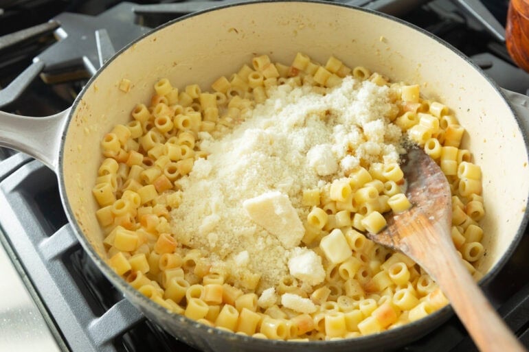 Close-up angle of butter Parmesan pasta in a dutch oven with freshly grated cheese on top.