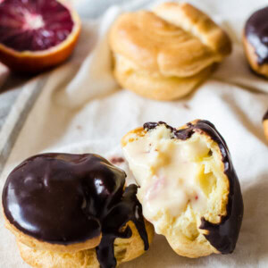 Cute little puffs are filled with sweet, blood orange cream and topped with a simple chocolate ganache to make these irresistible blood orange and chocolate cream puffs.