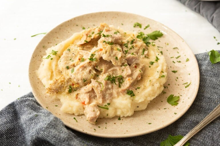 Tender slow cooker pork chops served with mashed potatoes and vegetables