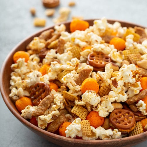 A bowl of 5 minute March madness snack mix. It has popcorn, cheese balls, pretzels, peanuts, and sesame sticks.