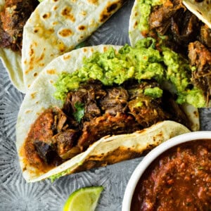 a photo of a shredded beef taco on a flour tortilla and topped with guacamole