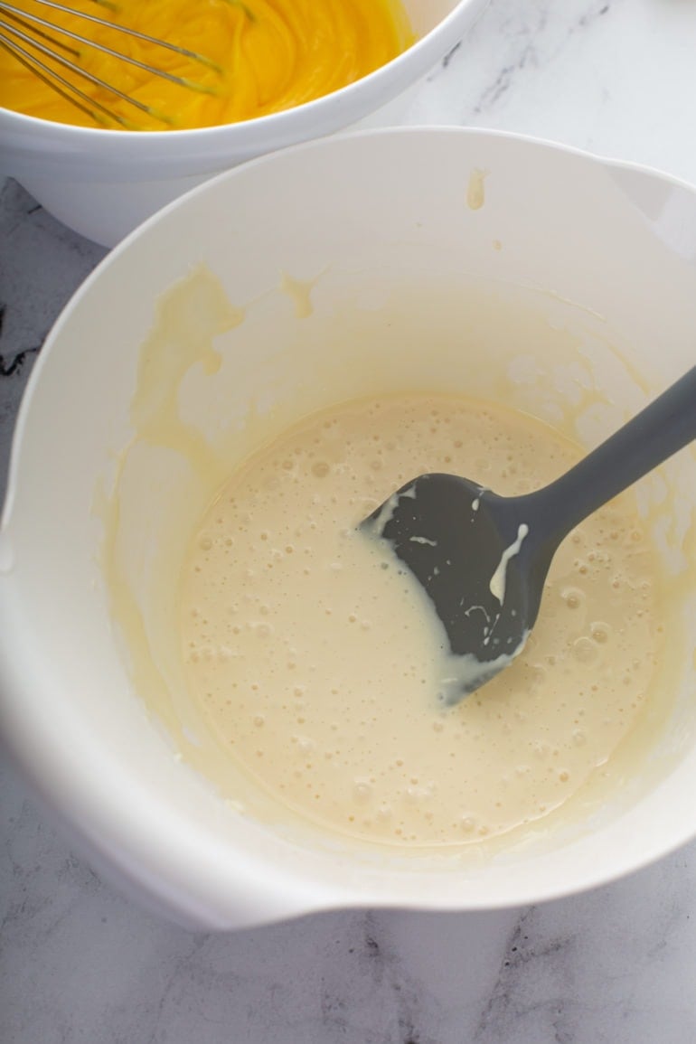 Cream cheese and sweetened condensed milk being mixed together in a mixing bowl.