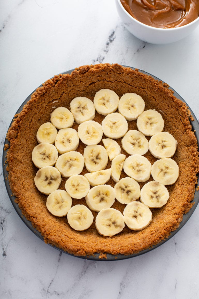 A graham cracker crust with sliced bananas covering the bottom of the crust.
