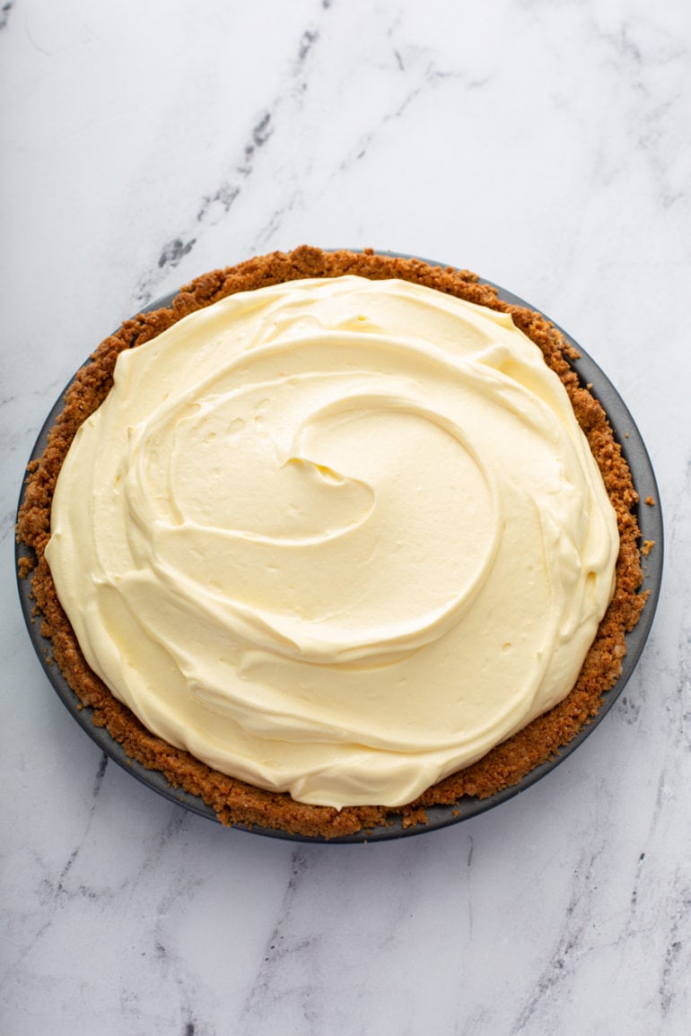 A banoffee pie in a graham cracker crust. The filling is light yellow and the crust is a deep graham cracker brown.