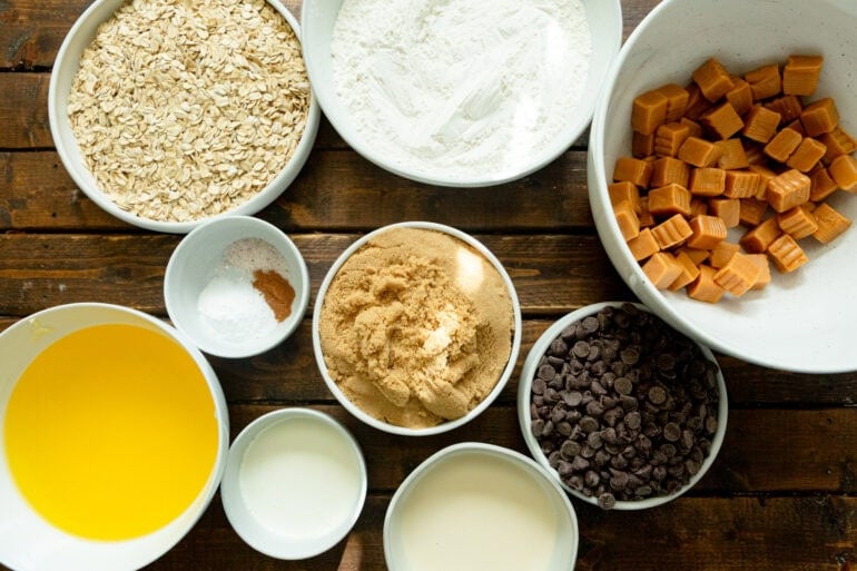 all the ingredients for carmelitas in small individual bowls including brown sugar, flour, salt, baking soda, oats, etc.