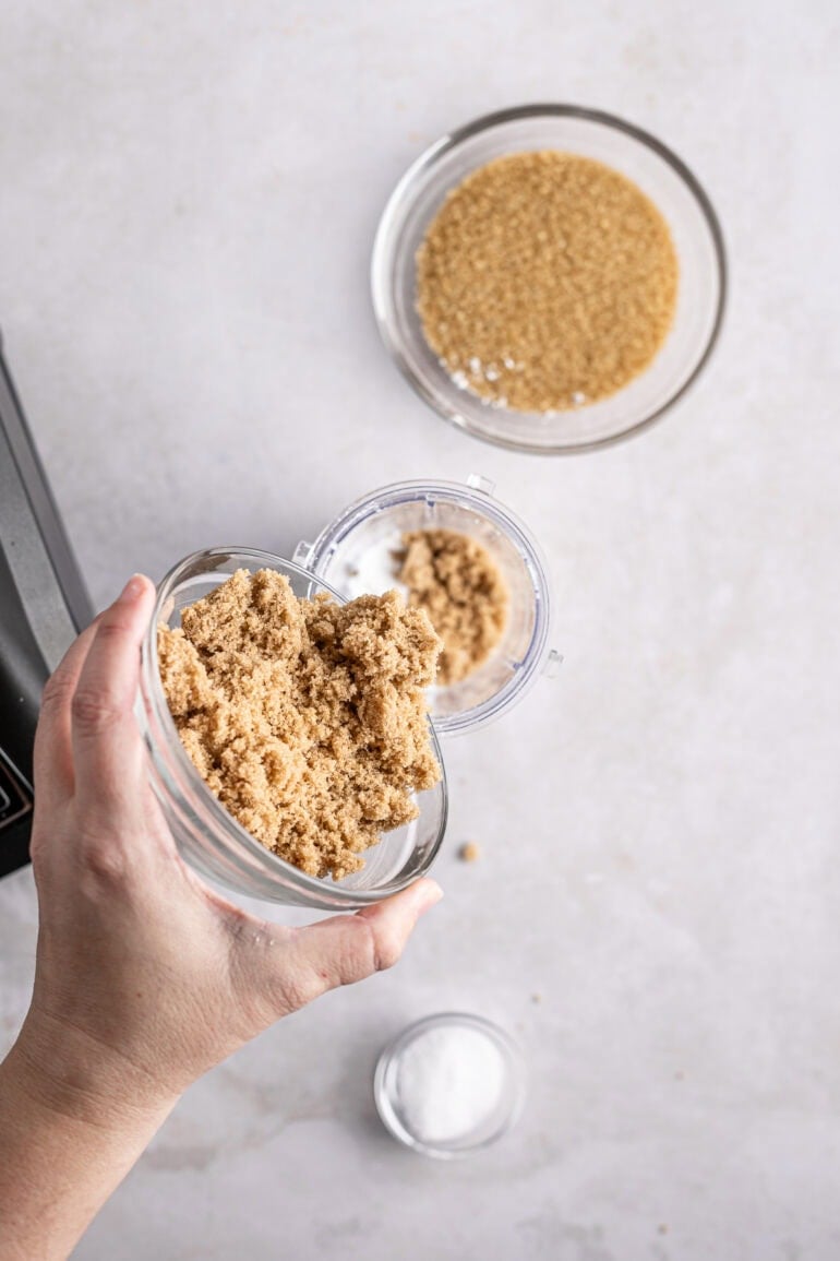 brown sugar being poured into a small bowl full of white sugar