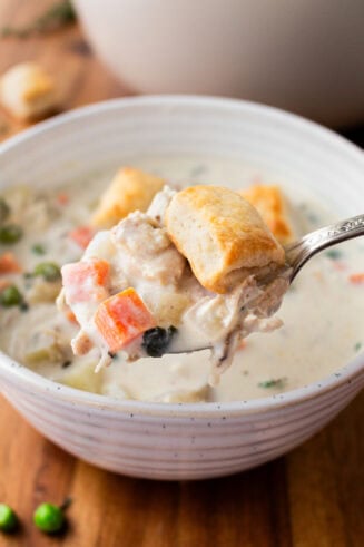 a photo of a bowl of creamy chicken pot pie soup topped with small golden biscuits