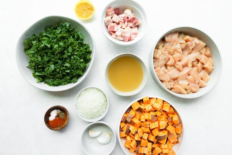 all the ingredients for sweet potato chicken skillet with kale including garlic, diced onions, chicken broth, spices, chicken, sweet potato and kale