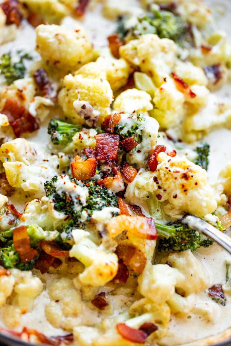 a phot of someone scooping up a serving of creamy parmesan garlic broccoli and cauliflower
