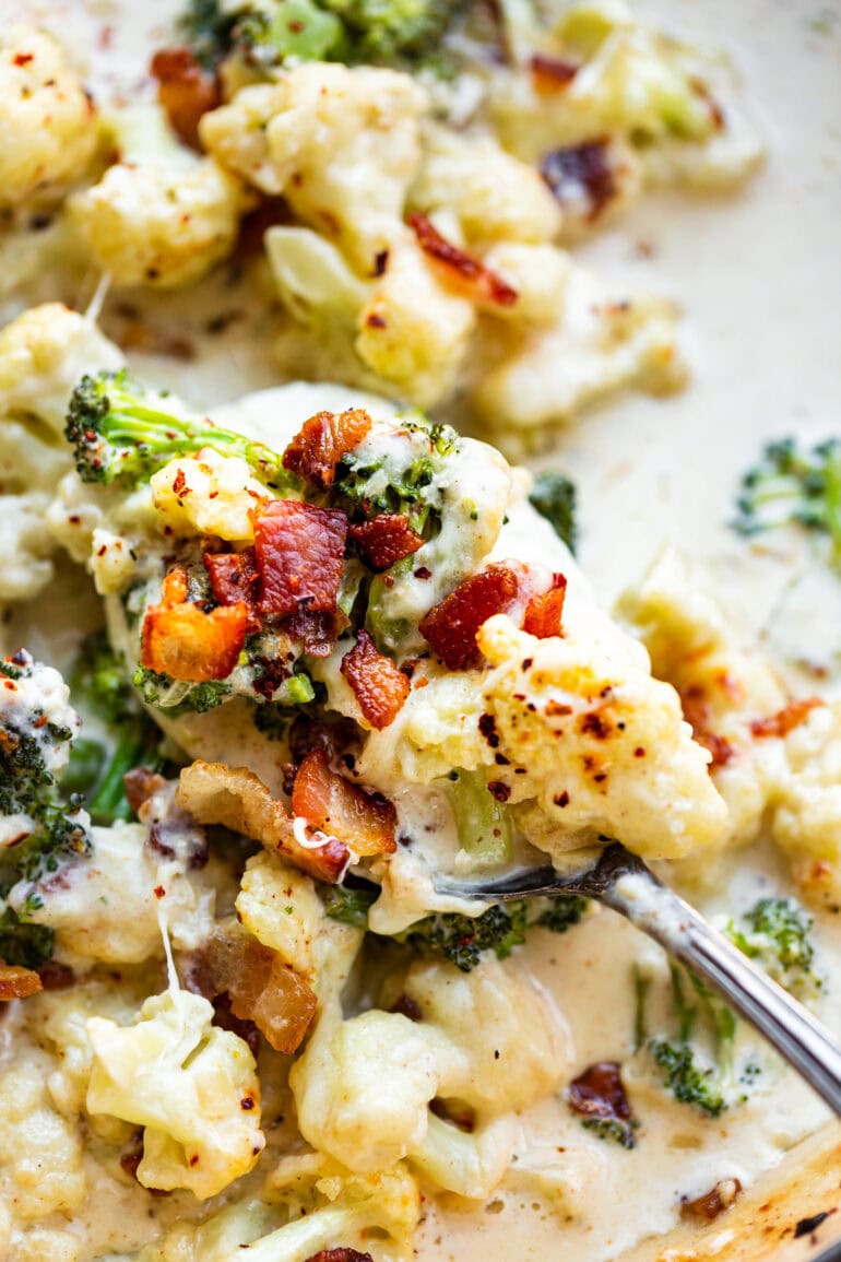 a photo of someone scooping out a bite of creamy garlic parmesan broccoli and cauliflower