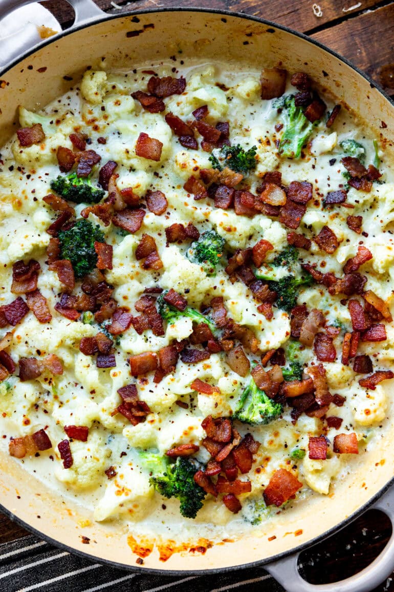 a photo of a large cast iron skillet full of creamy garlic parmesan broccoli and cauliflower