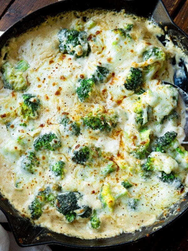 a photo of a large skillet filled with creamy broccoli topped with broiled cheese