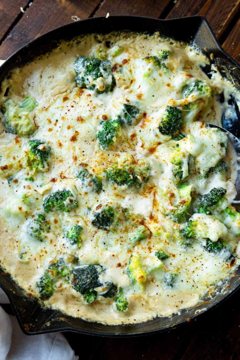 a photo of a large skillet filled with creamy broccoli topped with broiled cheese