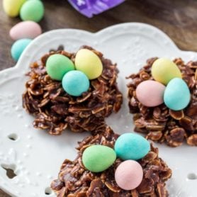 Three Easter Nest Cookies on a white plate topped with miniature eggs.
