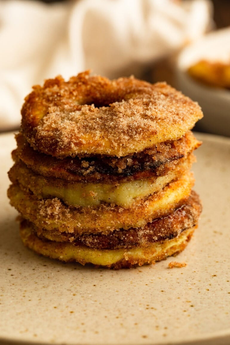 a stack of golden fried apple rings coated in cinnamon and sugar