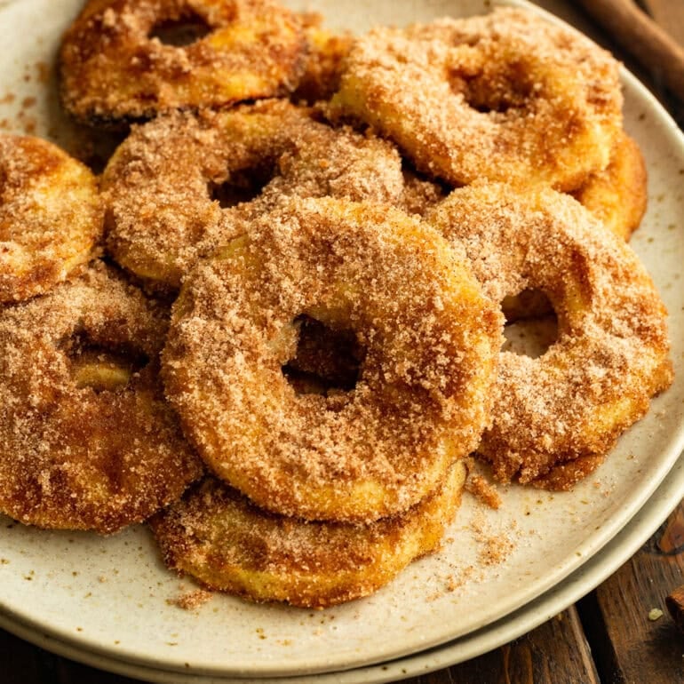 several air fried apple rings coated in golden batter and cinnamon sugar sitting on a plate