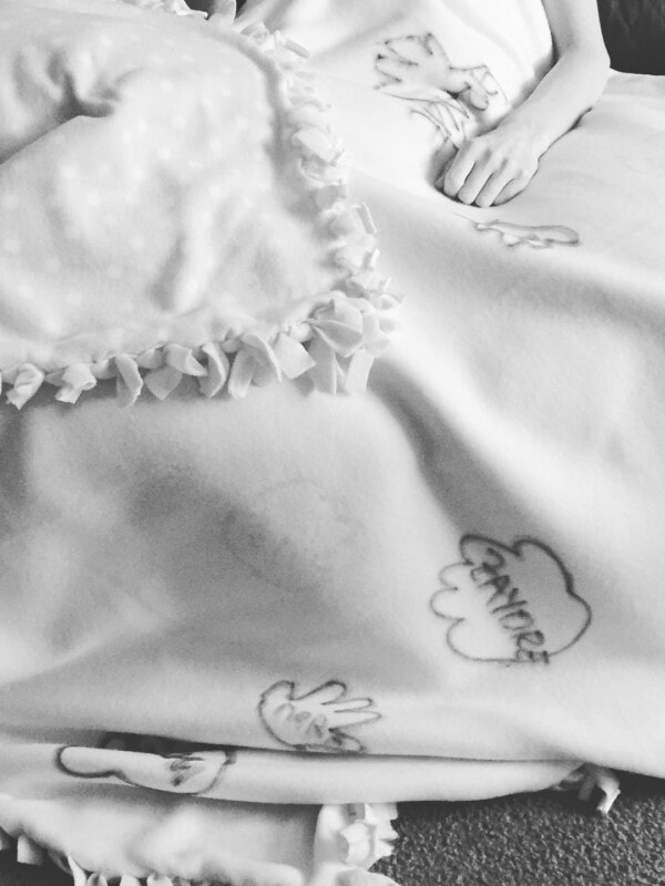 A photo of me laying underneath a blanket with handprints all over it.