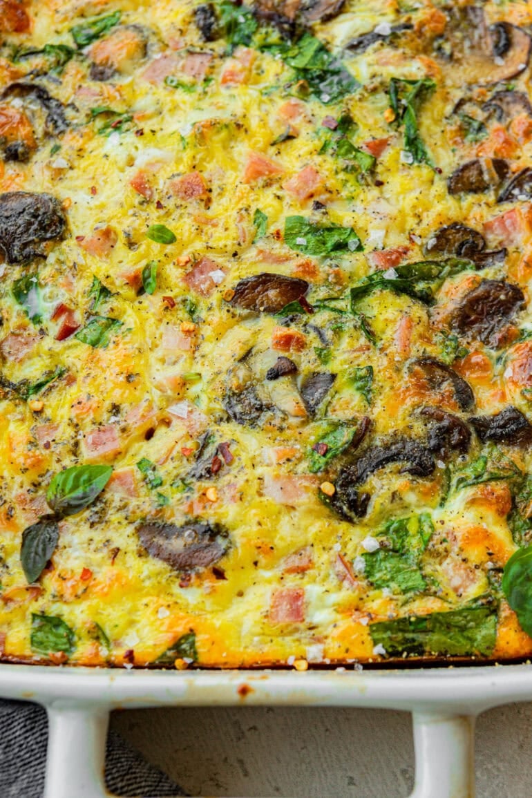 a baked egg casserole with sauteed mushrooms, spinach, cheese, and diced ham
