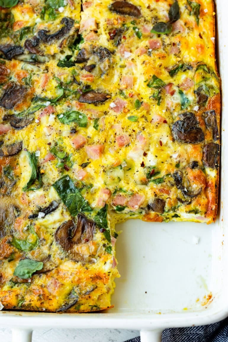 a baked breakfast egg casserole with a piece missing