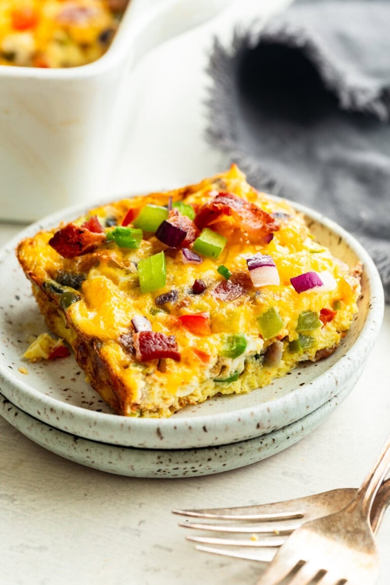 A baked egg casserole with bacon and peppers on a small plate