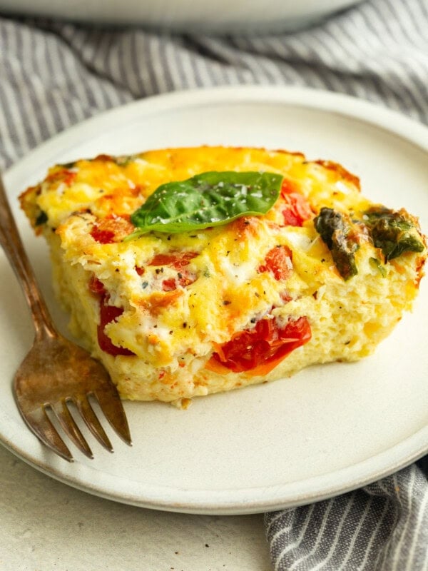 a serving of fluffy egg casserole with basil and tomatoes on a white plate