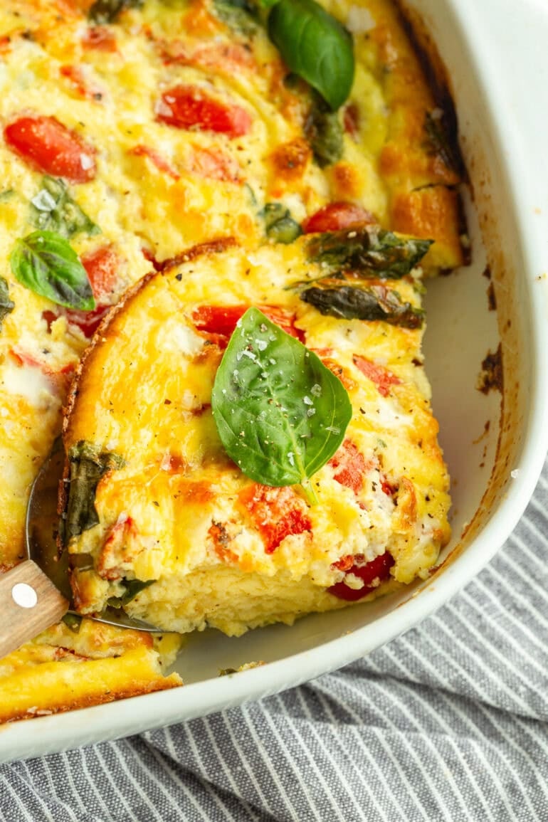 a serving of cottage cheese egg bake removed from a baking dish full of the casserole