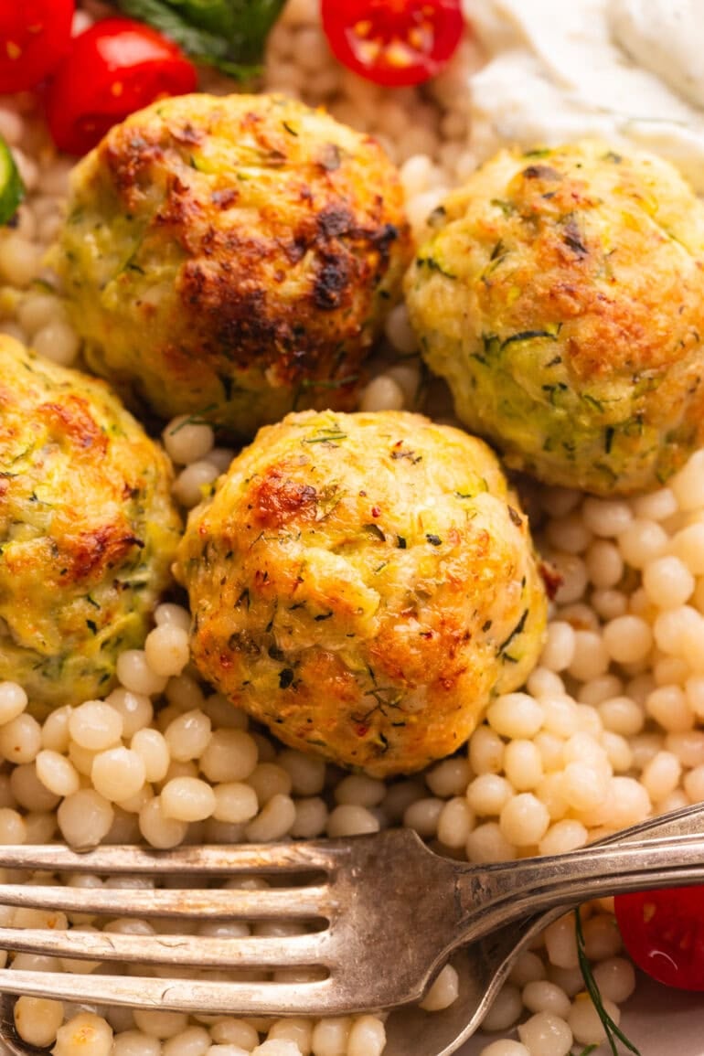 golden baked herb greek chicken meatballs on top of pearl cous cous