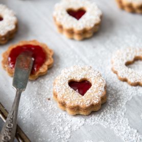 Linzer cookies with strawberry jam filling on a baking sheet