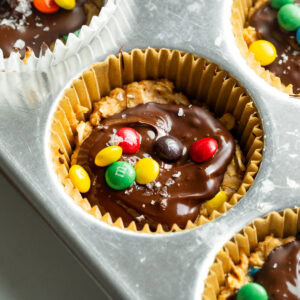 a muffin tin with each cup full of m&m peanut butter oat cups