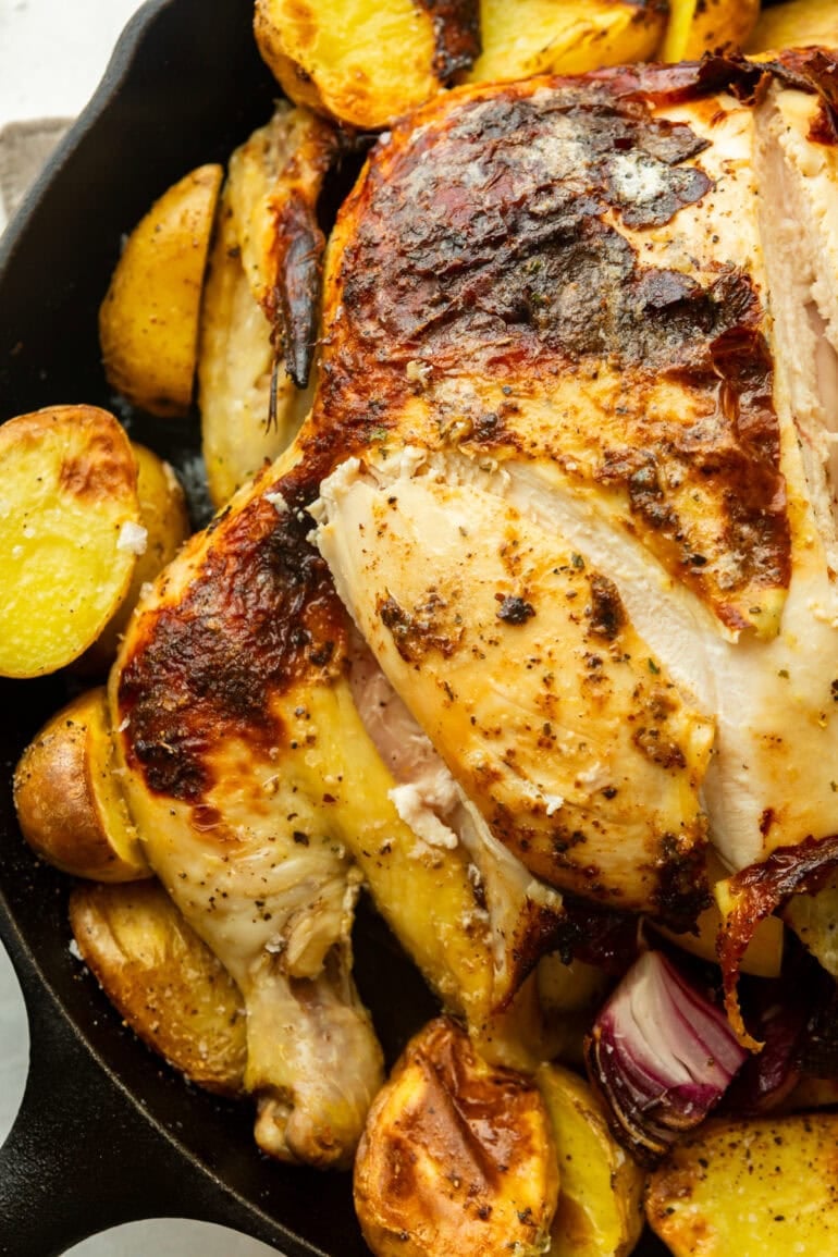 a whole roasted chicken with a slice of the breast cut off so you can see the juicy middle
