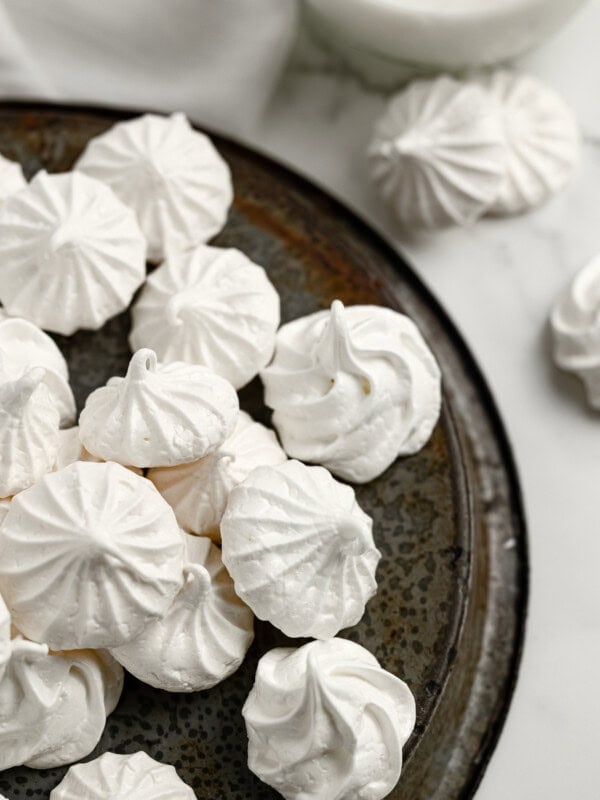 a metal serving tray full of small white meringue cookies