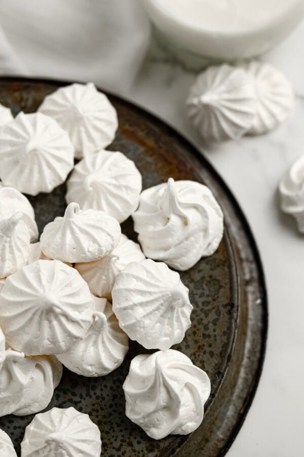 a metal serving tray full of small white meringue cookies