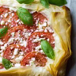 This Mozzarella Tomato Tart has a butter-garlic phyllo crust with mozzarella, tomatoes, feta, and basil. Makes a great appetizer or light meal for summer!