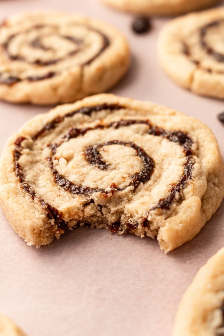Several pinwheel cookies with raisins, one with a bite taken out.