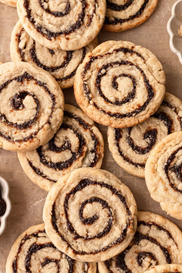 several baked raisin pinwheel cookies spread out on a piece of brown parchment paper