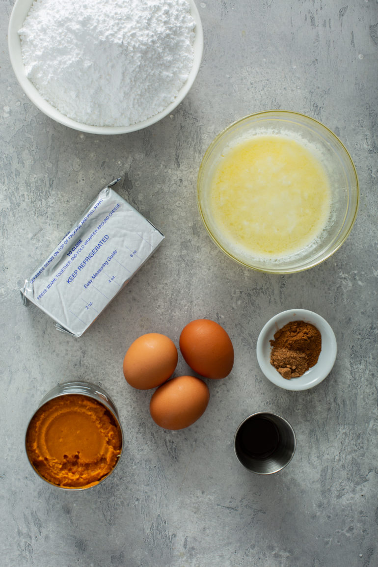 Ingredients for pumpkin gooey butter cake including cake mix, pumpkin puree, cream cheese, eggs, butter and spices