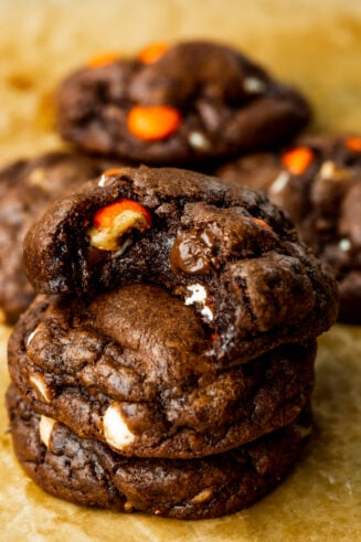 a photo of three triple chocolate Reese's cookies stacked on each other with a bite taken out of the top cookie