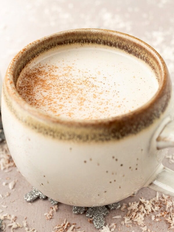 a photo of a mug full of warm vanilla milk and topped with a sprinkle of cinnamon