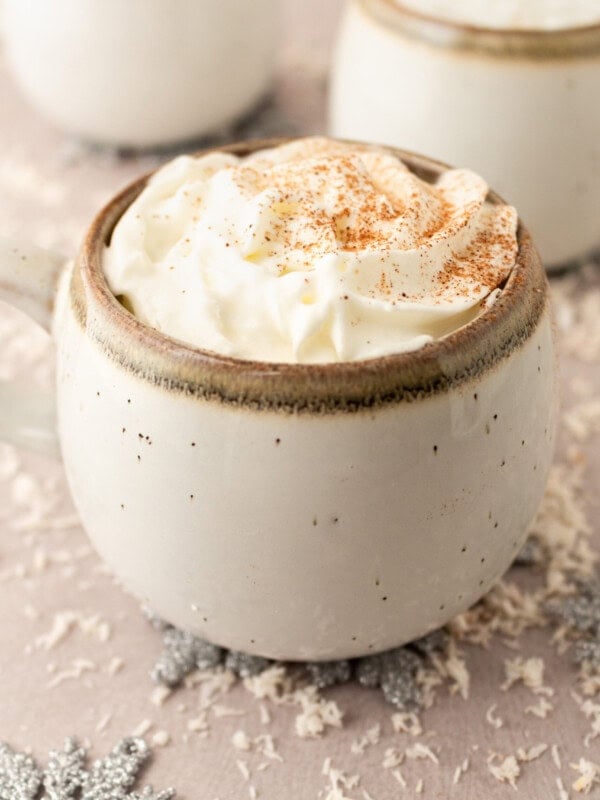 a photo of a mug of warm vanilla milk topped with whipped cream at sprinkled with cinnamon