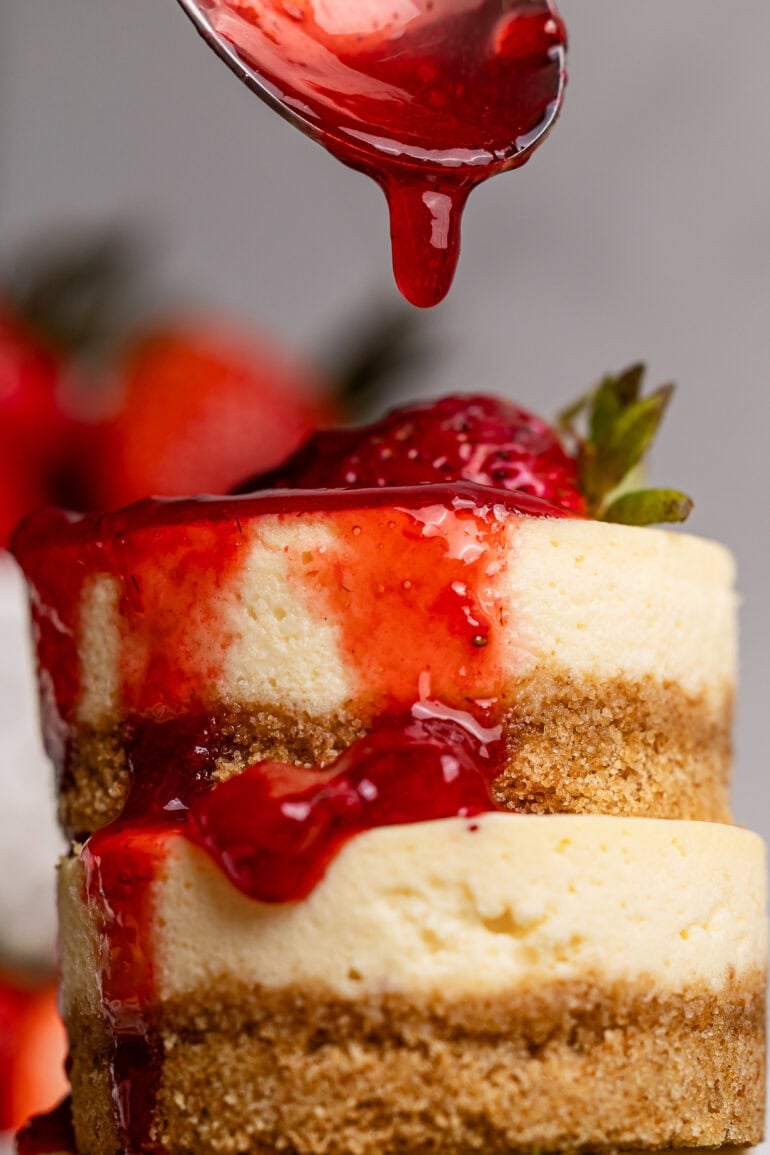 A stack of mini cakes and a spoon dripping berry topping over top of the stack.