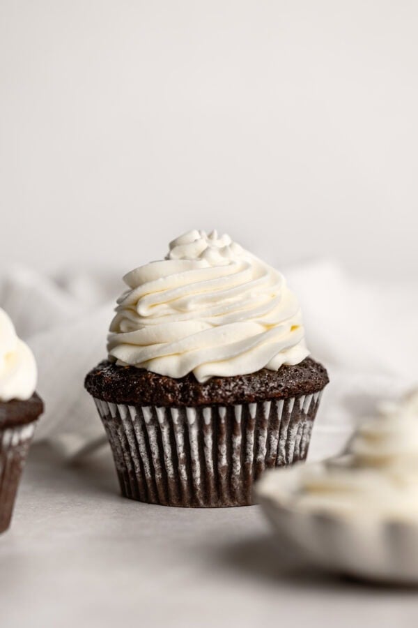a photo of a chocolate cupcake topped with a piped stack of whipped cream cream cheese frosting