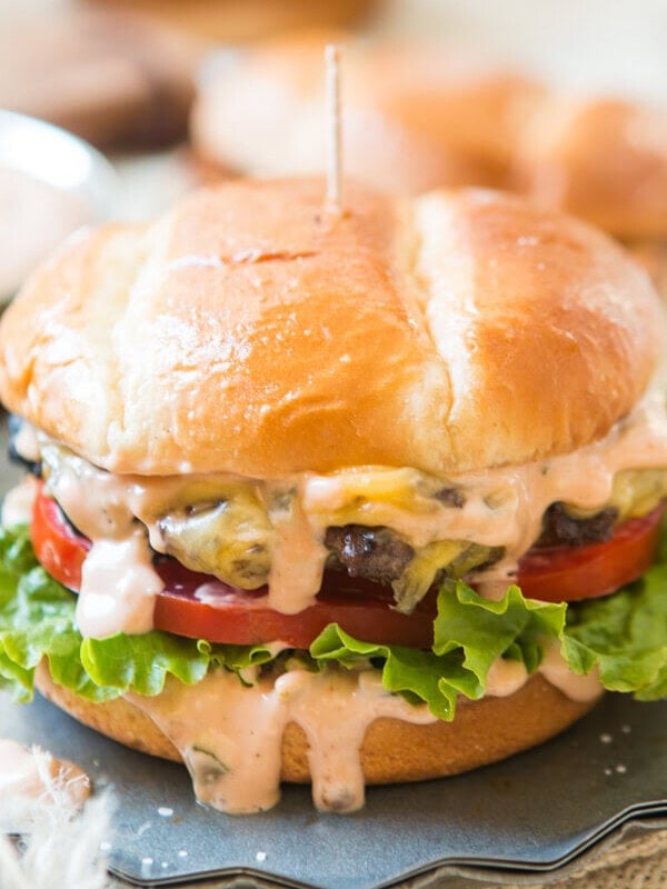 a melty cheese burger with lettuce and tomatoes with burger sauce dripping down the sides