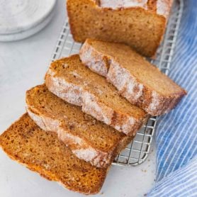 a photo of a loaf of baked amish friendship bread topped with cinnamon and sugar and half of the loaf cut into thick slices.