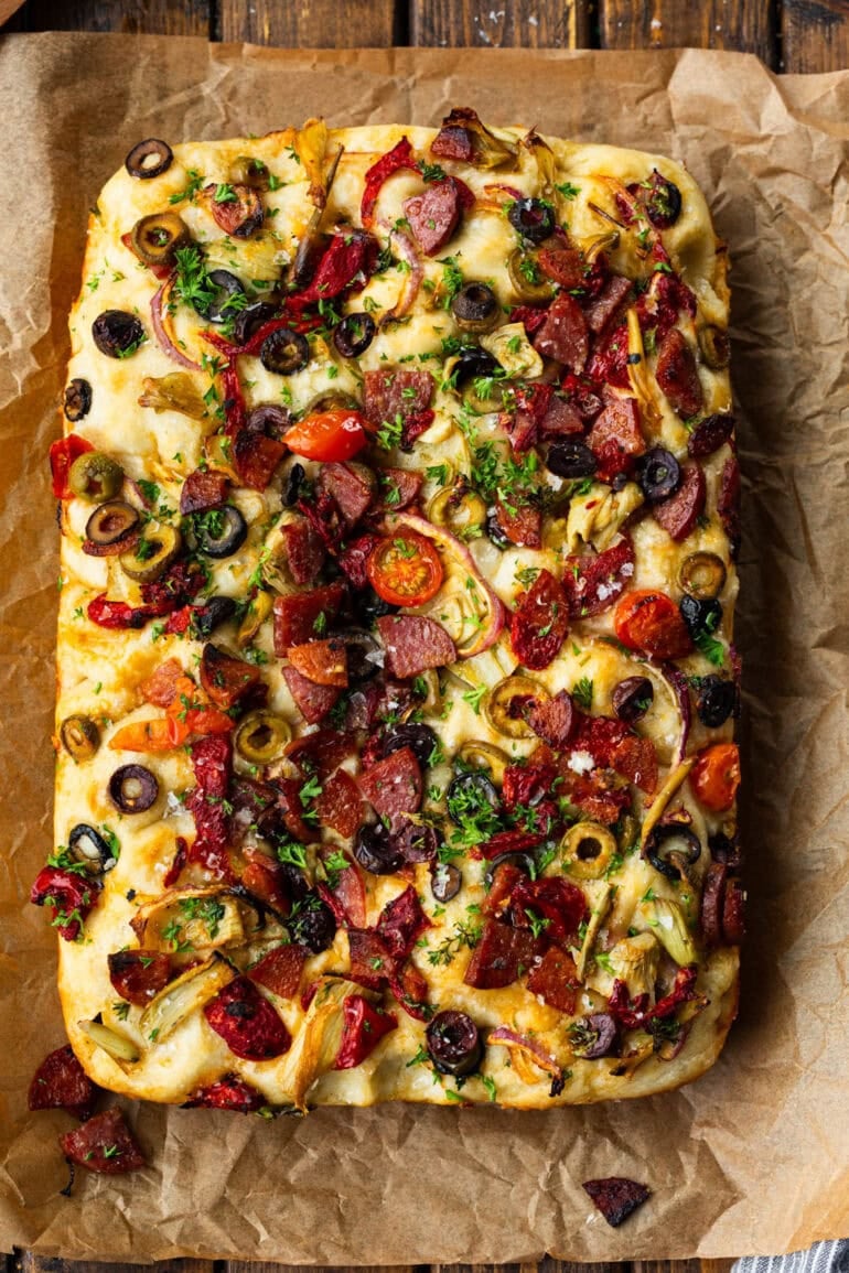 a rectangular loaf of baked focaccia great topped with chopped antipasto