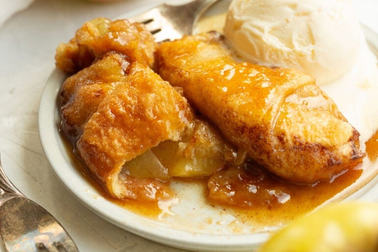 Close-up of a flaky apple dumpling filled with tender cinnamon sugar apples.
