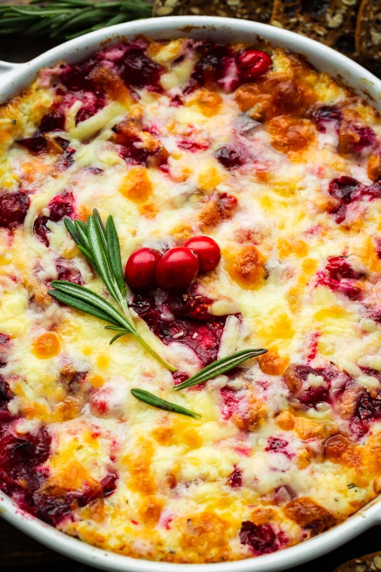 Roasted Cranberry Cream Cheese Sauce topped with melted cheese, a sprig of fresh rosemary and three whole cranberries