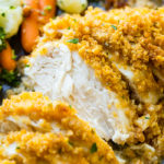 a grey plate full of steamed veggies and golden, baked quick and easy cornflake ranch chicken recipe which has been sliced into pieces of chicken