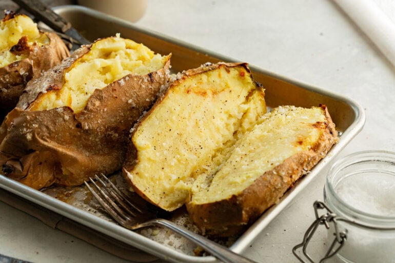 a baking dish with baked white sweet potatoes in it that have been sliced in half